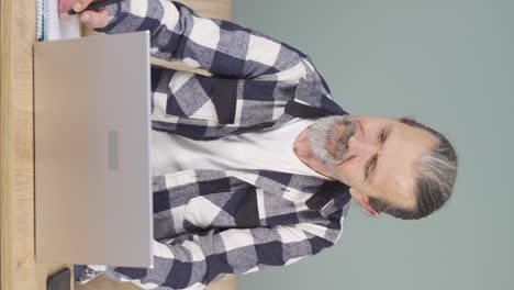 Vertikales-Video-Eines-Alten-Mannes,-Der-Mit-Glücklichem-Gesichtsausdruck-Am-Laptop-Arbeitet.